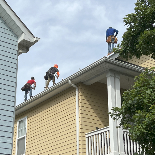 Workers installing roofing on house