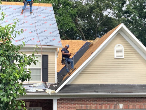 Workers installing a roof on house
